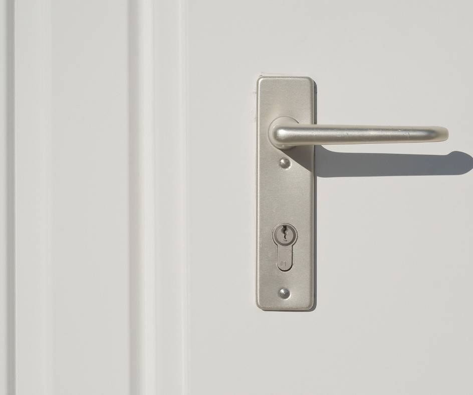 Białe drzwi i srebrna klamka w drzwiach